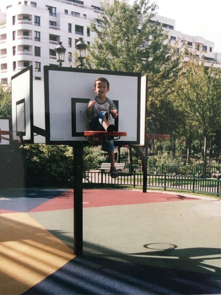儿子爬上了儿童公园的篮球架